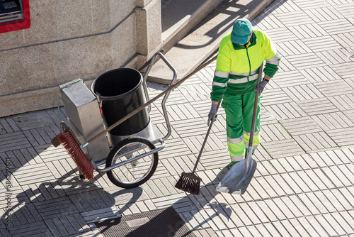 Φωτογραφία Street sweeper working on a sidewalk with her shovel, trolley and broom