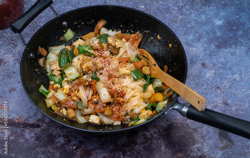 Vegan noodles, tofu and vegetable mix stir fry in wok,