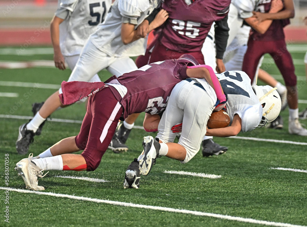 Young athletic young boys playing in a competitive game of tackle football and making incredible game winning plays Young athletic young boys playing in a competitive game of tackle football and making incredible game winning plays