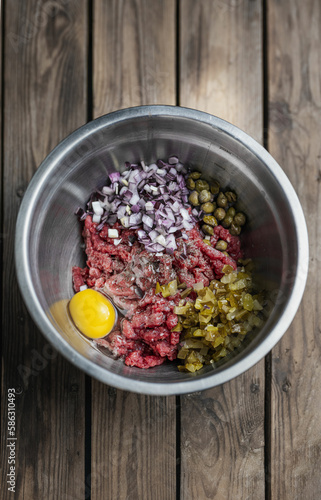 beef tartare on a dark plate in the hands of a man photo