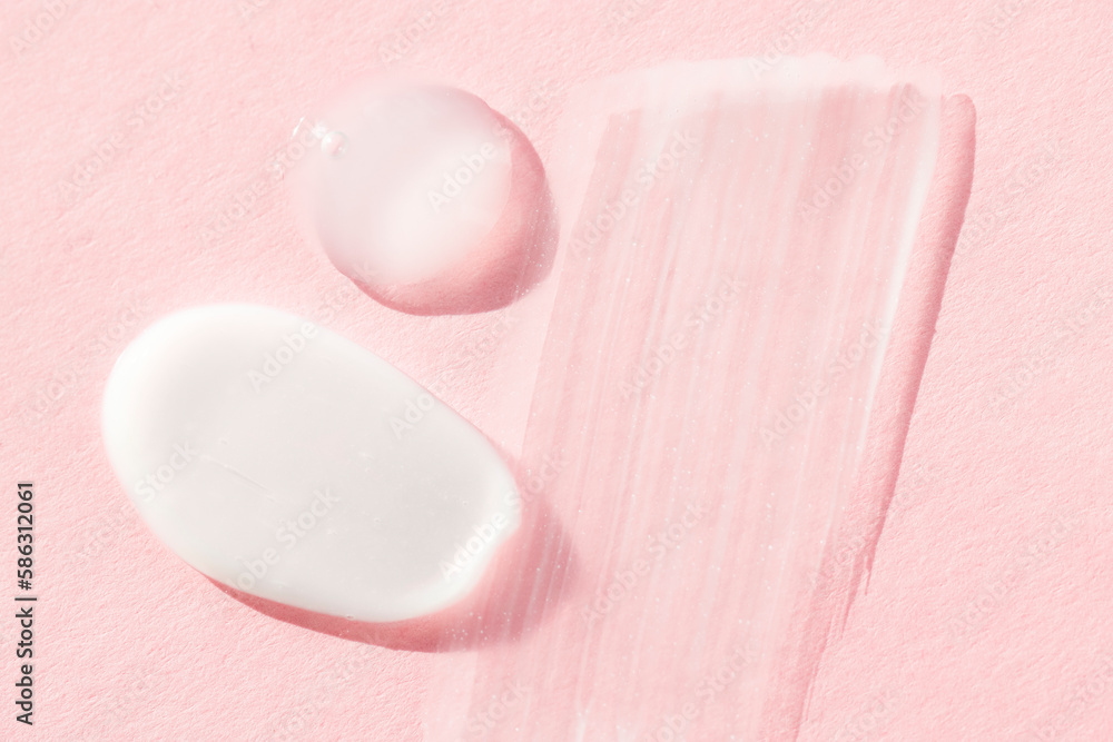 Smears of white cosmetic cream on a pink background, top view. Liquid care products, textures of hyaluronic acid, lotion, foam close-up. Smears of white cosmetic cream on a pink background, top view. Liquid care products, textures of hyaluronic acid, lotion, foam close-up.