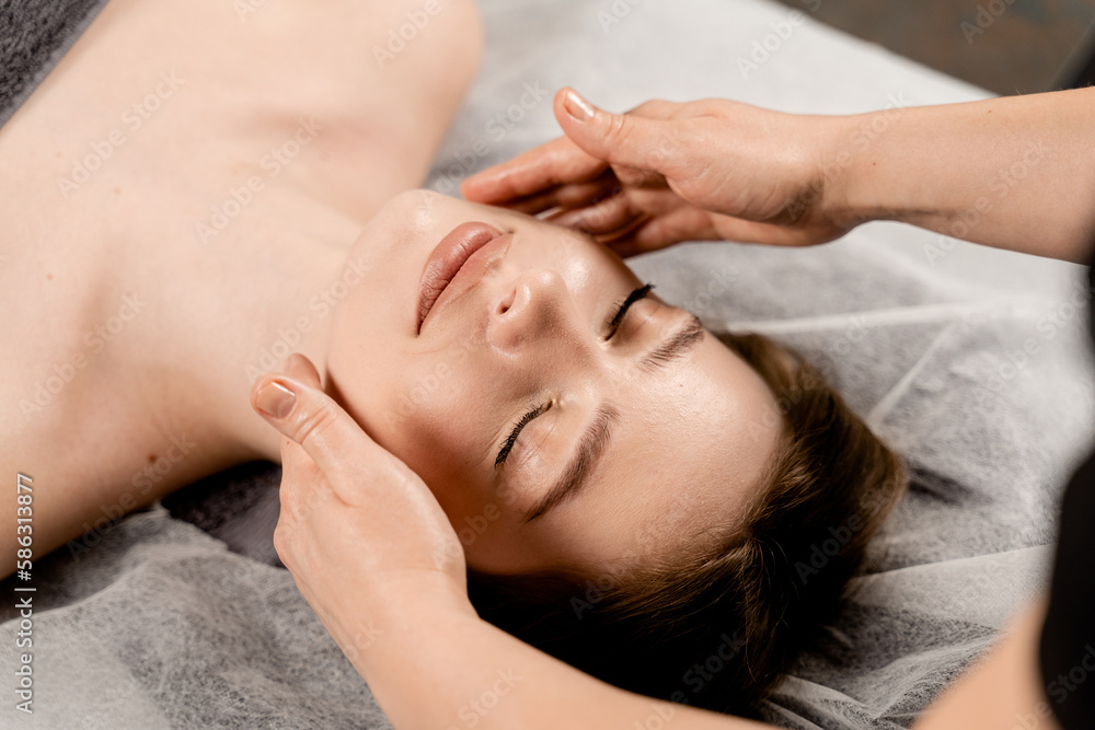 Masseur is making facial beauty treatments for attractive female model. Neck and face massage in the spa. Relaxation. Masseur is making facial beauty treatments for attractive female model. Neck and face massage in the spa. Relaxation.