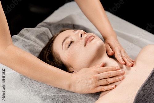 Neck and face massage in the spa. Masseur is making facial beauty treatments for attractive female model. Relaxation.