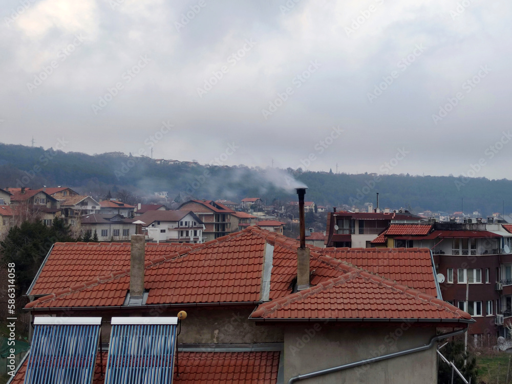 Smoke from a chimney on a tiled roof in a Bulgarian house