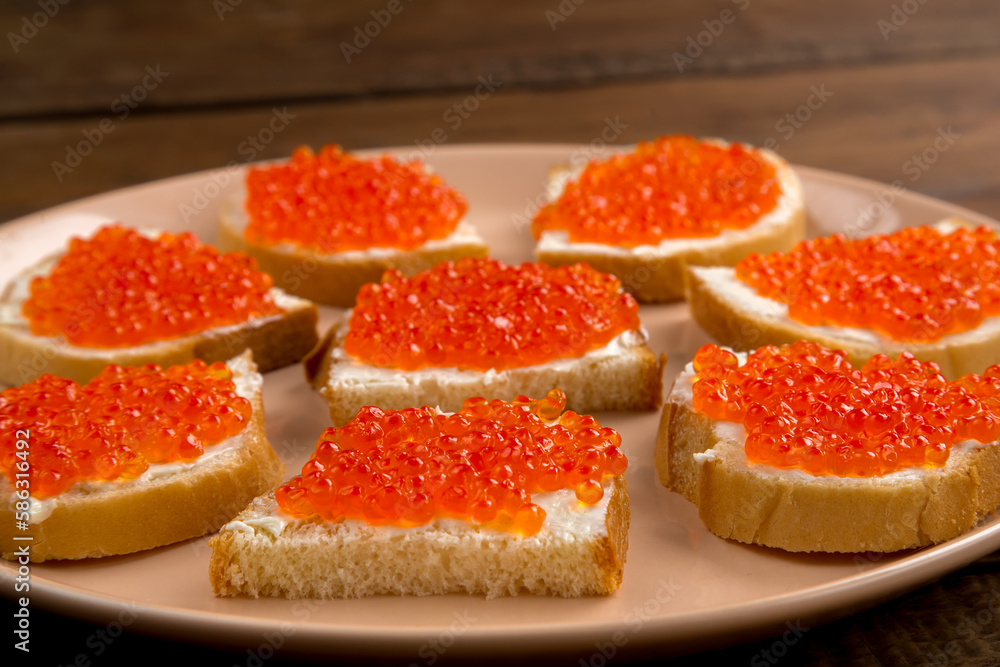 Canape with red caviar in butter on a beige plate. Canape with red caviar in butter on a beige plate.