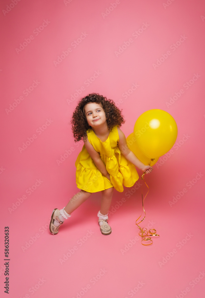 Portrait of a cheerful little girl isolated on a pink background, holding a bunch of colorful balloons, posing. Portrait of a cheerful little girl isolated on a pink background, holding a bunch of colorful balloons, posing.