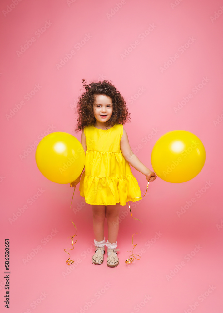 Portrait of a cheerful little girl isolated on a pink background, holding a bunch of colorful balloons, posing. Portrait of a cheerful little girl isolated on a pink background, holding a bunch of colorful balloons, posing.