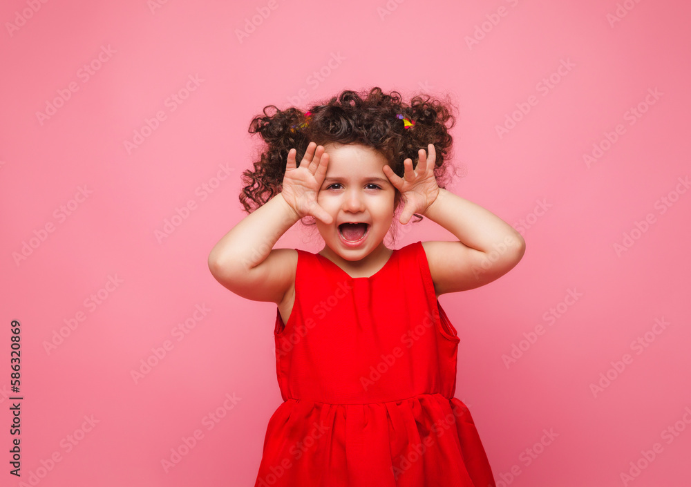 emotional portrait of a little girl in a red dress on a pink background. emotional portrait of a little girl in a red dress on a pink background.