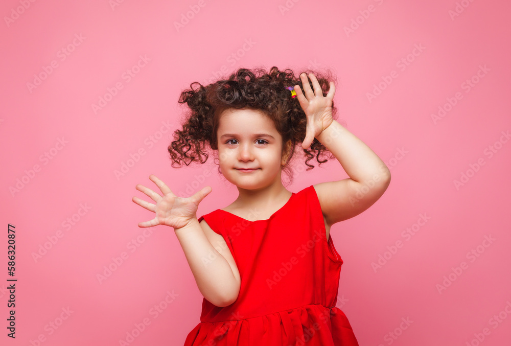 emotional portrait of a little girl in a red dress on a pink background. emotional portrait of a little girl in a red dress on a pink background.