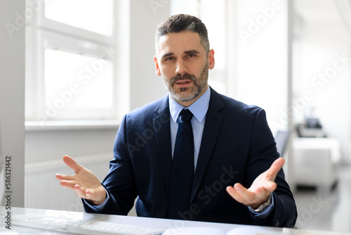 Portrait of confident middle aged businessman having virtual online meeting, talking and gesturing to camera