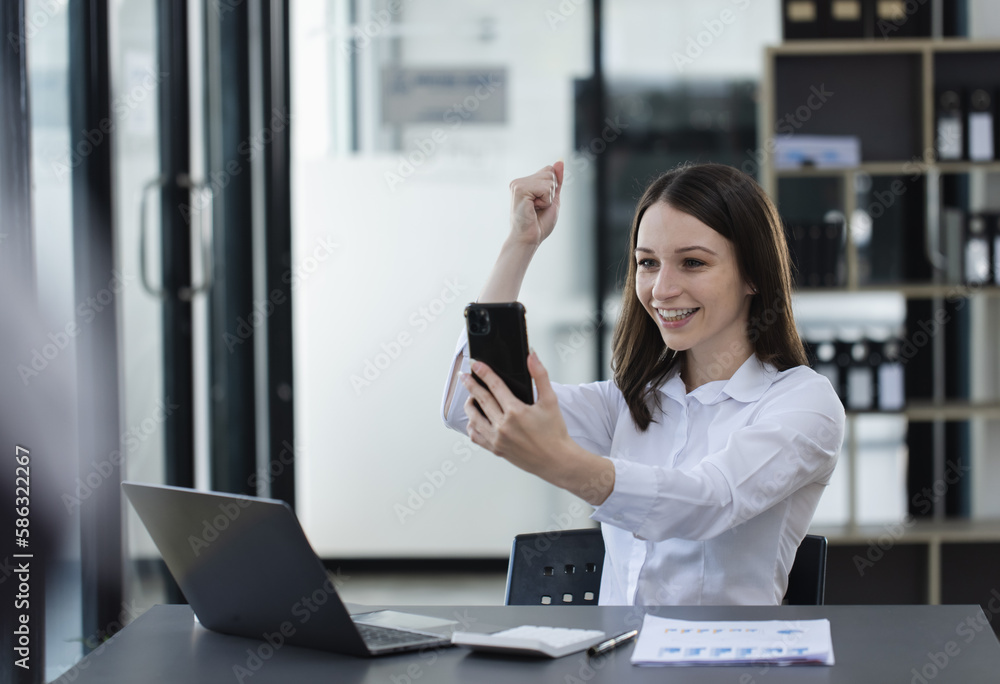 Happy excited young successful business woman and working online at the table in office, Happy excited young successful business woman and working online at the table in office,