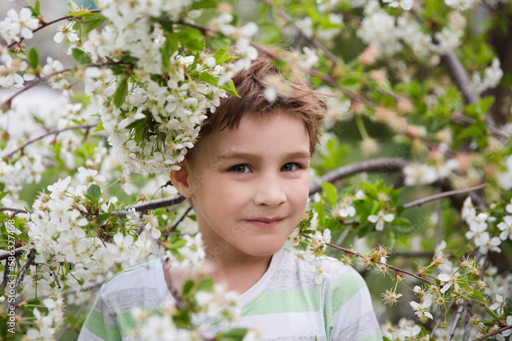 portrait of a kid boy next to a flowering cherry tree against a green grass background. portrait of a kid boy next to a flowering cherry tree against a green grass background.