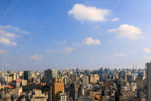 Cidade de S  o Paulo vista do alto  com edif  cios  torres antenas e c  u azul com nuvens.