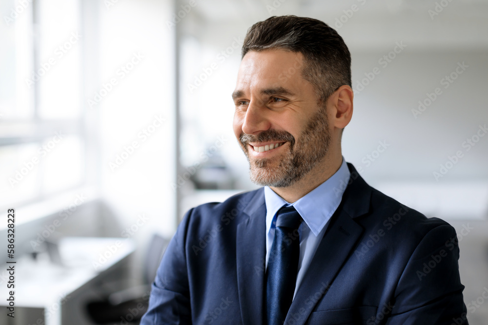 Successful business person. Portrait of happy businessman in suit looking aside at free space, posing in office