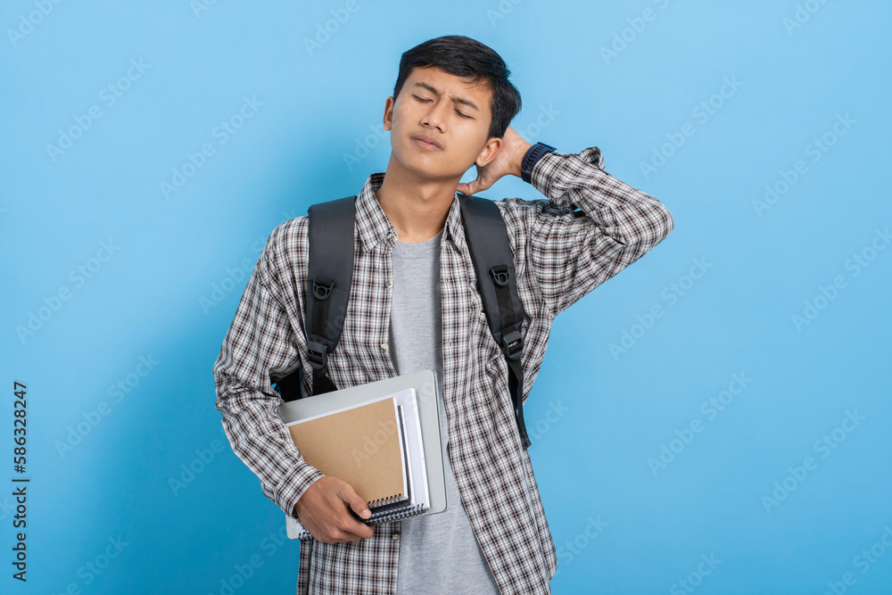 Young asian college student carrying books and backpack feeling sick tired and frustration isolated over blue background Young asian college student carrying books and backpack feeling sick tired and frustration isolated over blue background