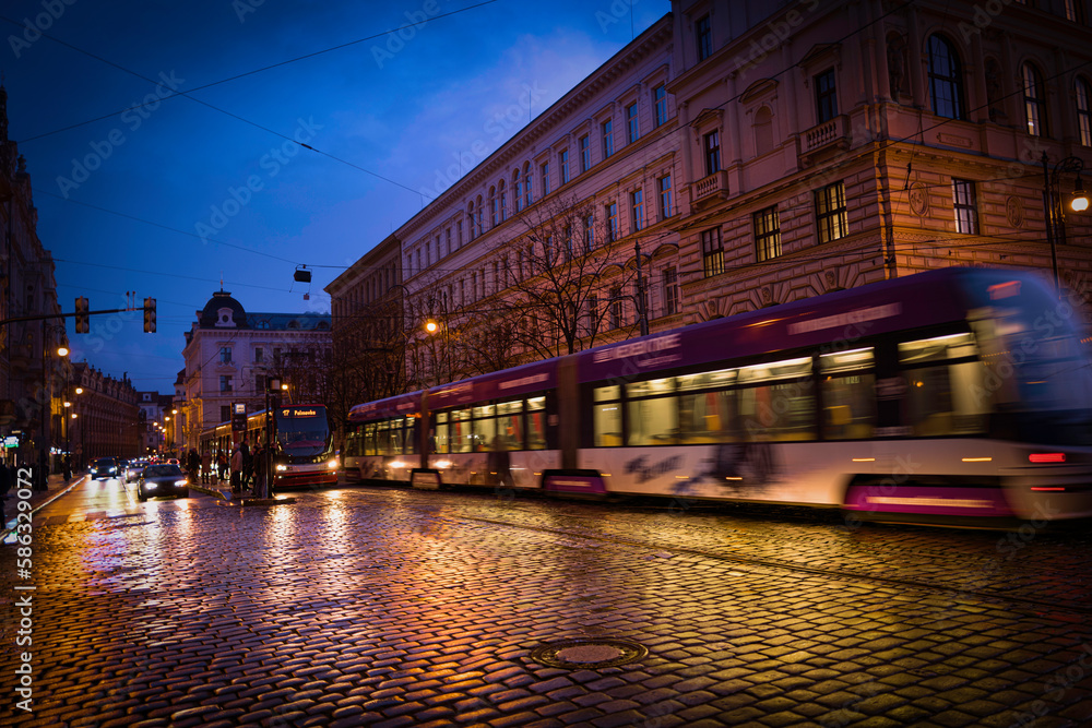 Prague city downtown street rainy landscape with buildings and cars at dusk with reflections on the sidewalk in Czech Republic