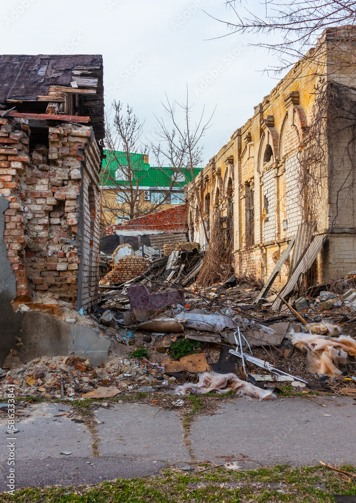 Ruins of abandoned houses in a modern city. The wall of the building collapses, bricks fall. Depressive view along the street