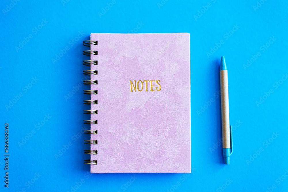 Pink notepad and craft pen on a blue background. Pink notepad and craft pen on a blue background.