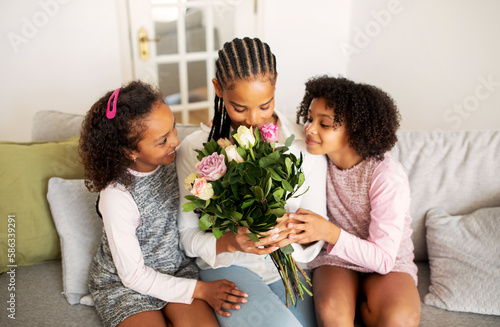Daughters Giving Flowers To Mom Greeting Her Celebrating Holiday Indoors