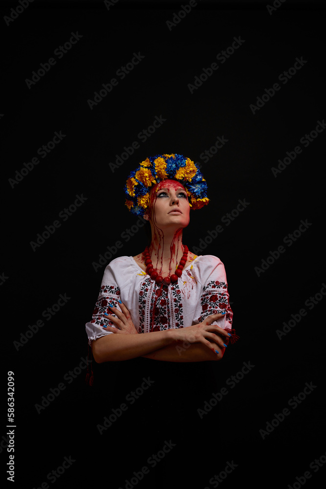 portrait of a girl in Ukrainian national clothes and jewelry with a wreath of blue and yellow flowers, blood on her face as a symbol of the war in Ukraine on a black background, vertical