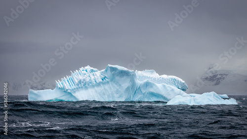 Impressive iceberg with blue ice and beautiful reflection on water in Antarctica, scenic landscape in Antarctic Peninsula 