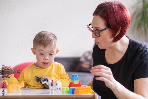  little boy living with down syndrome playing home with toys showing facial expressions, exploring
