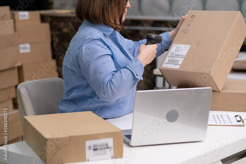dropshipping business. woman with laptop scanning barcodes to track delivery to online customers