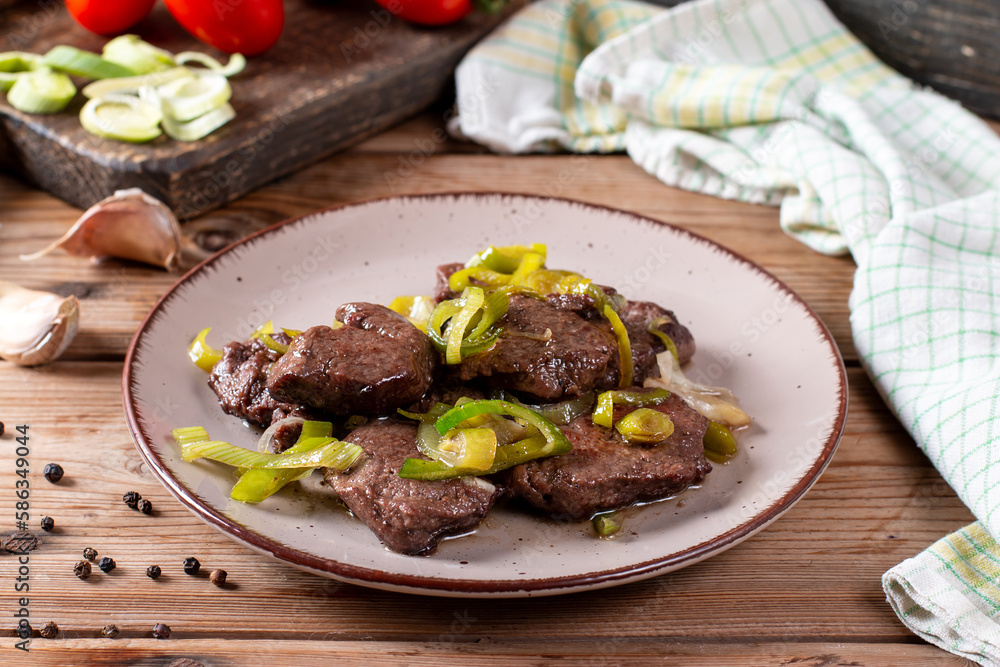 Rare roasted thick juicy beef fillet medallion topped with leek on wooden table Rare roasted thick juicy beef fillet medallion topped with leek on wooden table