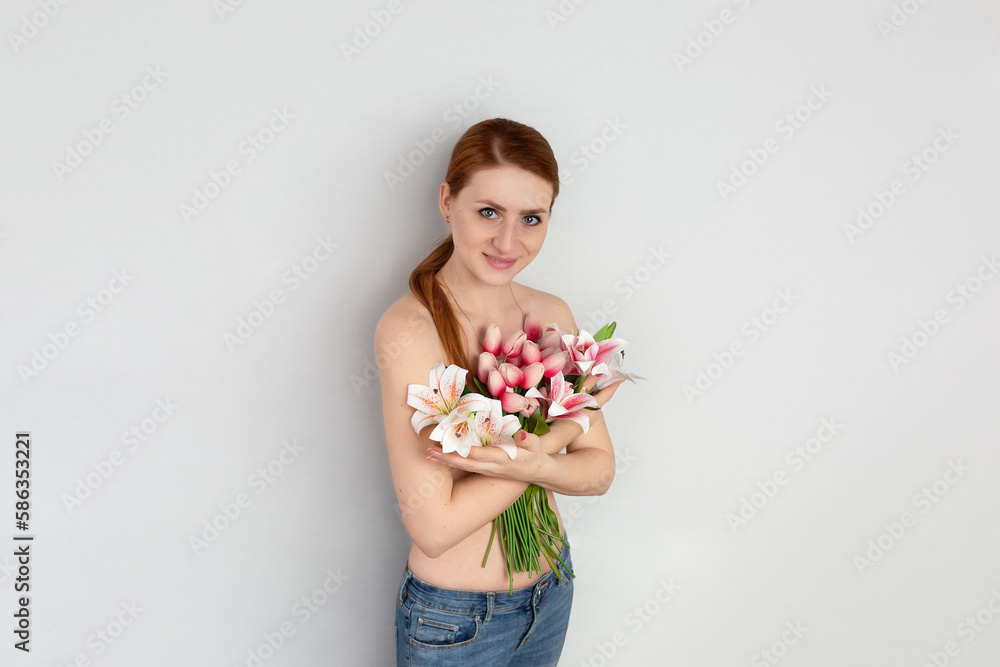 Young happy smiling redhead woman holding a bouquet of tulips on a white background. Festive bouquet in honor of Women's Day on March 8 or birthday. hugging flowers Young happy smiling redhead woman holding a bouquet of tulips on a white background. Festive bouquet in honor of Women's Day on March 8 or birthday. hugging flowers