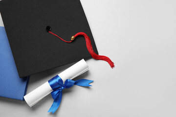 Diploma with blue ribbon, graduation hat and book on white background