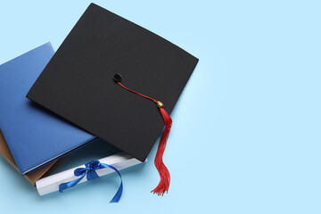 Diploma with ribbon, graduation hat and books on blue background