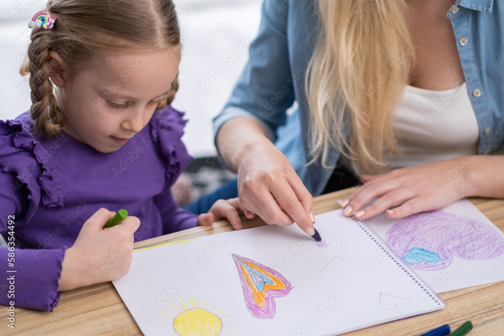 Close up on little girl painting at home with mom using crayon and pencils - Back to school Close up on little girl painting at home with mom using crayon and pencils - Back to school
