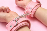 Woman with handcuffs from sex shop on pink background, closeup
