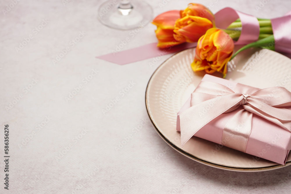 Clean plate, gift box, tulip flowers and wine glass on white grunge table Clean plate, gift box, tulip flowers and wine glass on white grunge table