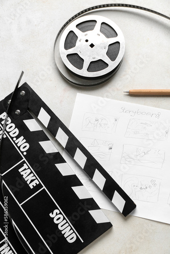 Movie clapper with storyboard and film reel on light background