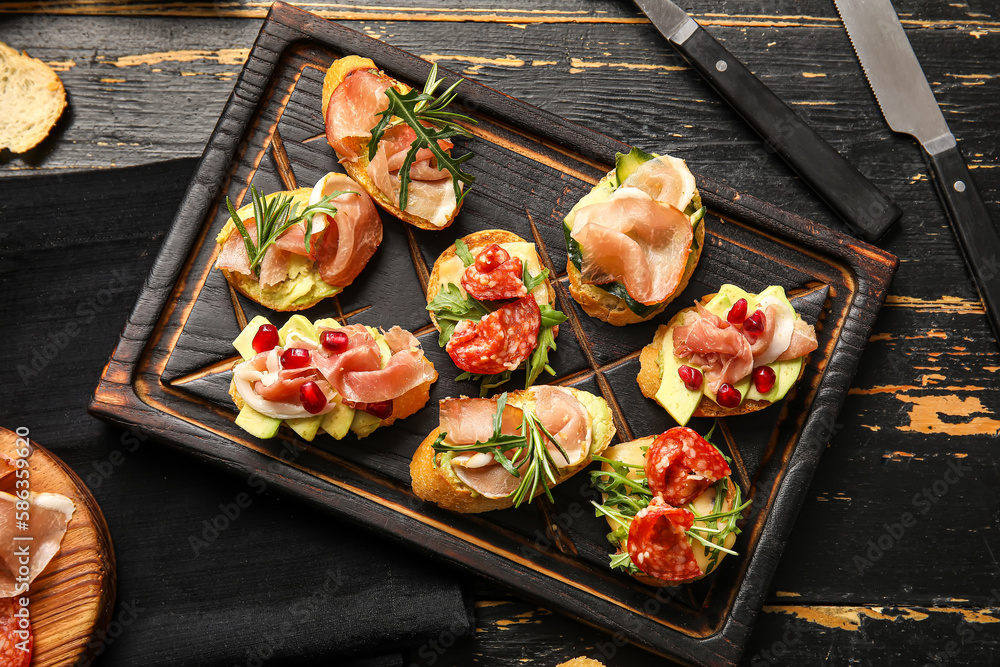 Board of tasty bruschettas with ham on dark wooden background Board of tasty bruschettas with ham on dark wooden background