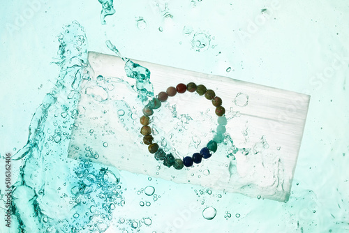 Chakra bracelet on quartz crystal with water splash