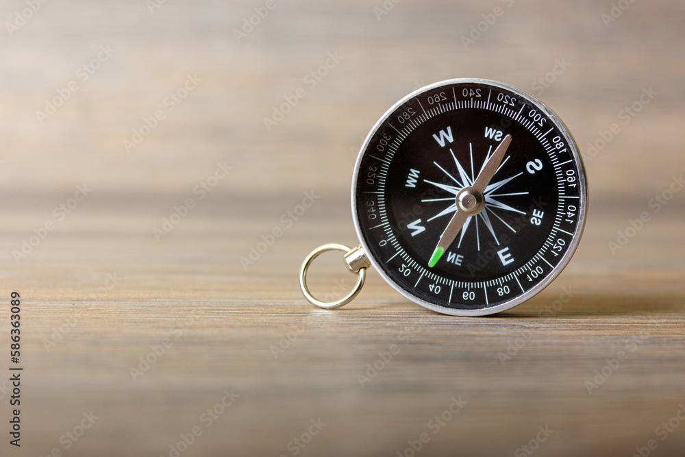 Compass stands on a natural wooden table Compass stands on a natural wooden table