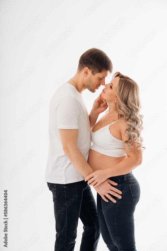 a couple waiting for a child in white T-shirts and jeans on a white background. a couple waiting for a child in white T-shirts and jeans on a white background.
