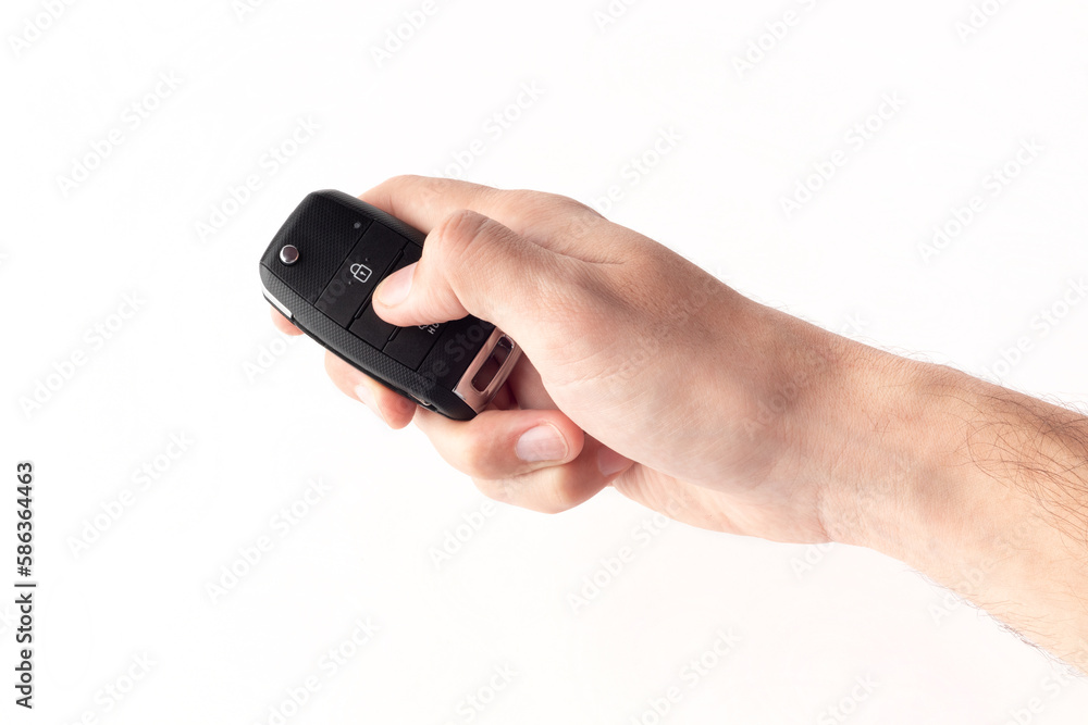 Unlocking a car with button on the keychain. Man's hand holds car key on white background close up. Unlocking a car with button on the keychain. Man's hand holds car key on white background close up.
