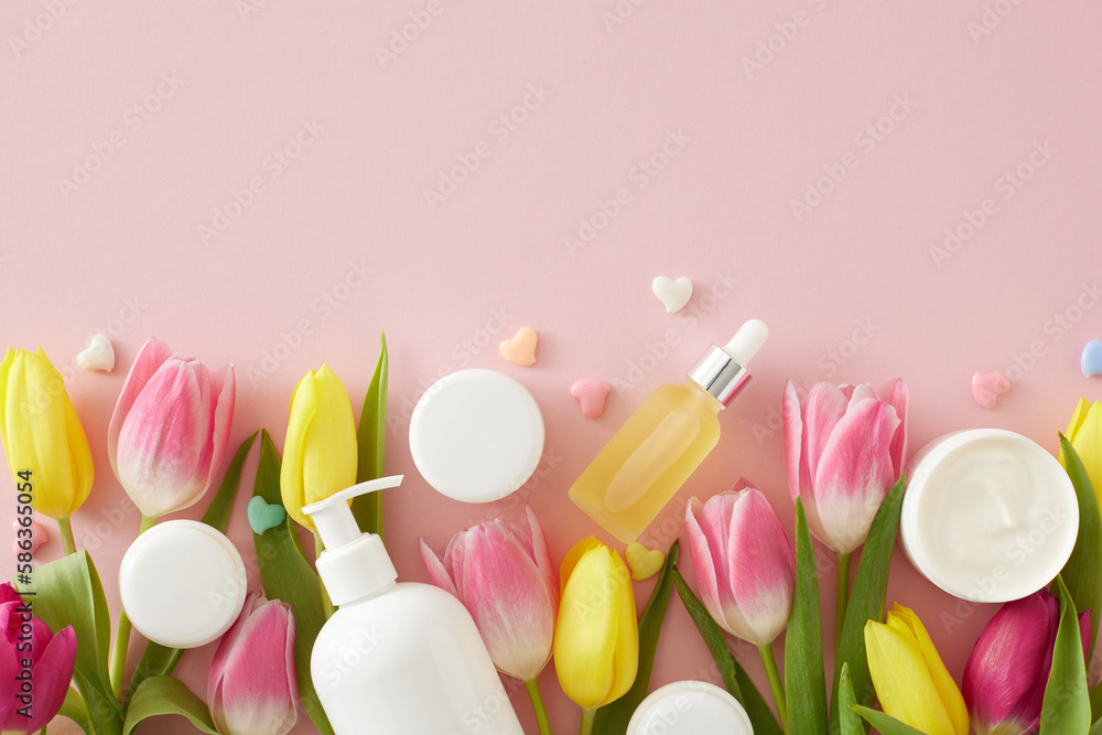 Organic skincare concept. Top view photo of dropper bottle pump bottle without label cream jars colorful hearts and pink yellow tulips on isolated pastel pink background with copyspace