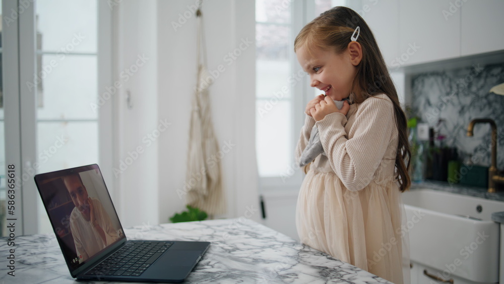 Lovely child waving laptop at kitchen close up. Happy daughter speaking remotely Lovely child waving laptop at kitchen close up. Happy daughter speaking remotely