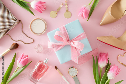 Top view photo of giftbox with bow perfume bottle cosmetics and bijouteries beige women shoes handbag watches and pink tulips on pastel pink background. Mother's Day concept