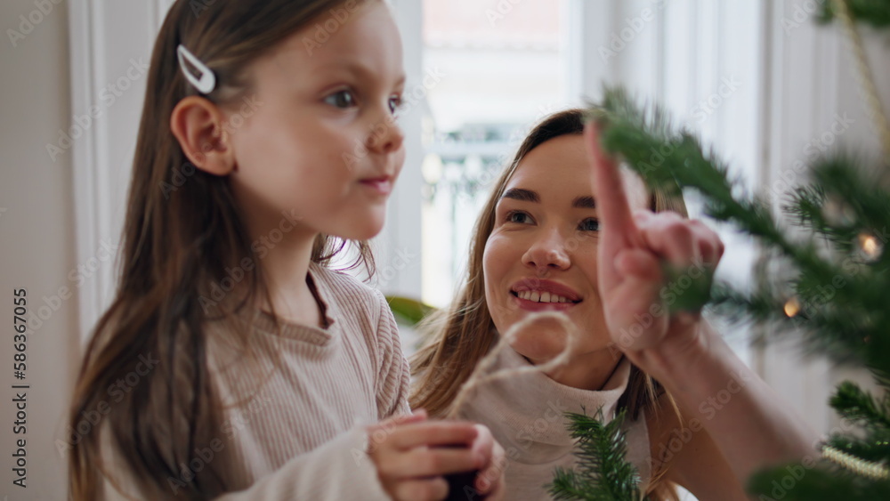 Affectionate kid putting xmas toys on branches portrait. Woman helping child Affectionate kid putting xmas toys on branches portrait. Woman helping child