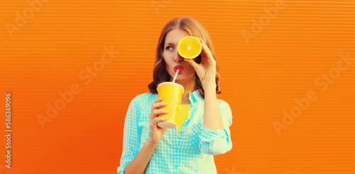 Summer portrait of happy young woman drinking fresh juice with slice of orange fruits on background