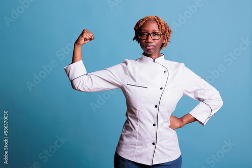 Canvas Print African american woman wearing kitchen uniform flexing arm muscles in front of camera