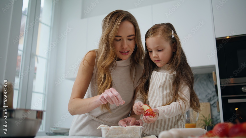 Curious daughter decorating cake with mom kitchen closeup. Woman teach kid bake