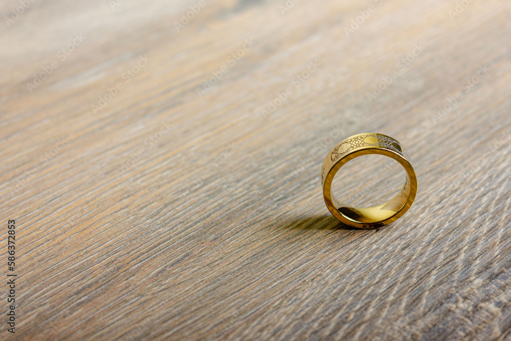 An isolated golden ring stands on a wooden table An isolated golden ring stands on a wooden table