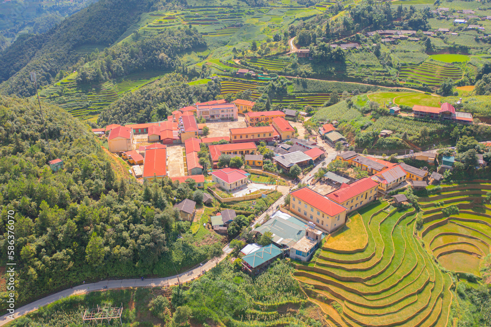 Aerial top view of Mu Cang Chai City urban town with fresh paddy rice, green agricultural fields in countryside or rural area, mountain hills valley in Asia, Vietnam. Nature landscape background.