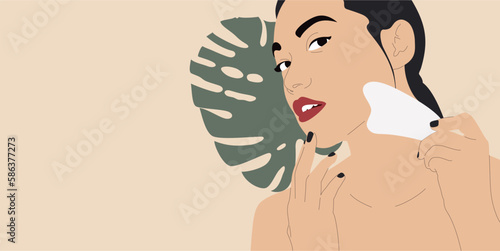 Beautiful young woman doing facial massage with Gua Sha tool